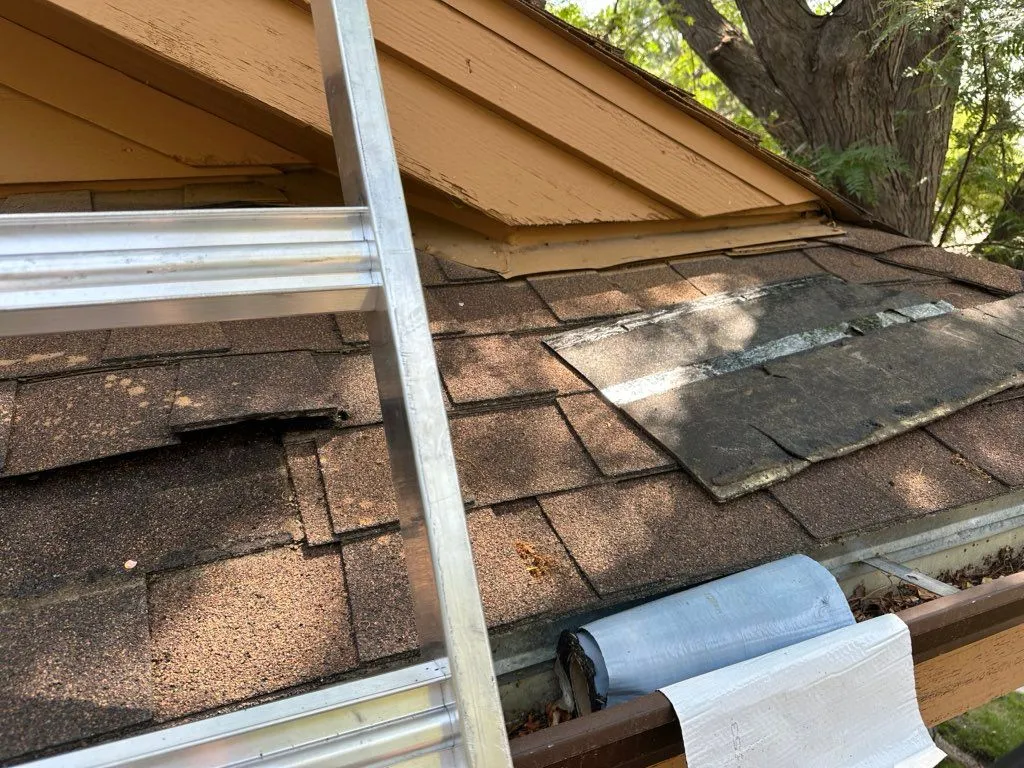 Worn asphalt shingle roof with a ladder and repair membrane during a roof repair