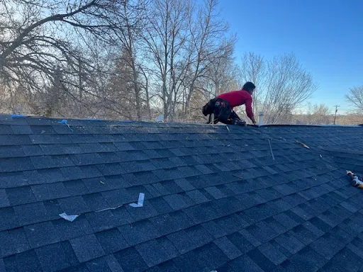Roofer working on a newly installed dark asphalt shingle roof