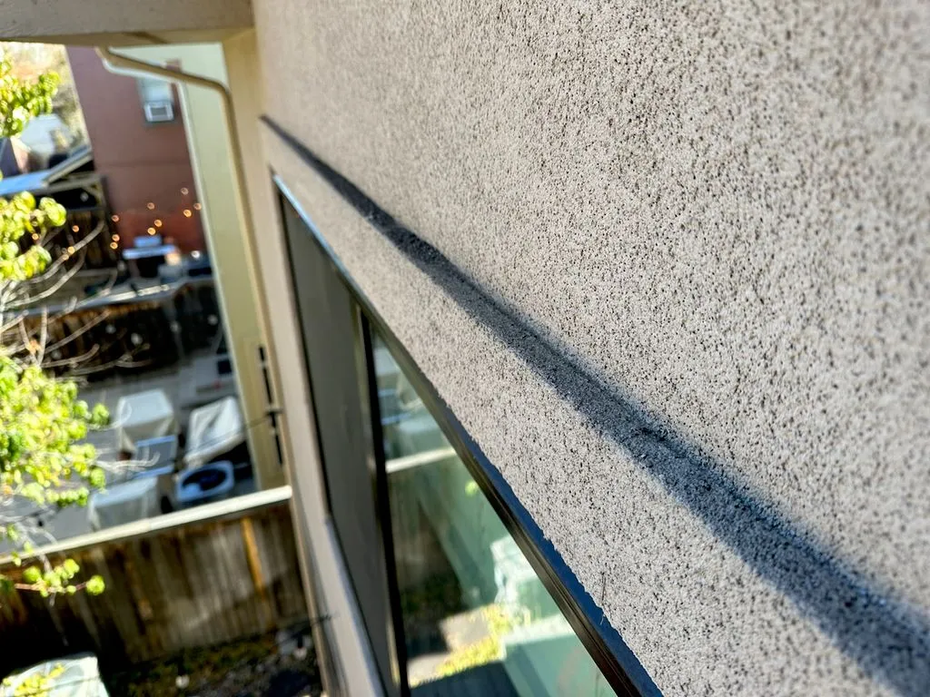 Newly applied stucco band above a window, photographed from ladder height