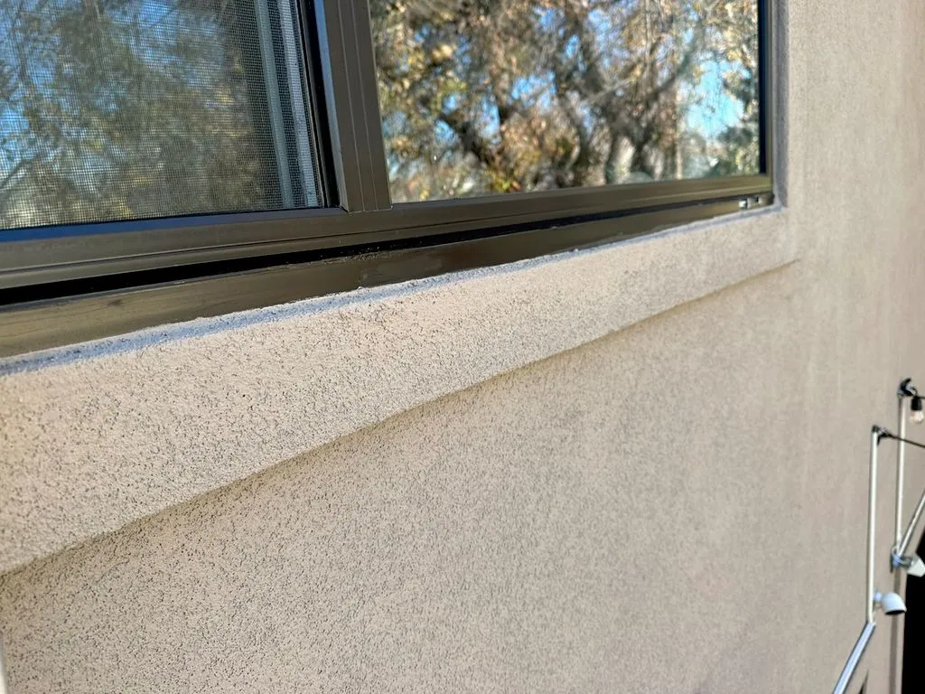 Fresh stucco finish on the sill band below a window after a stucco repair